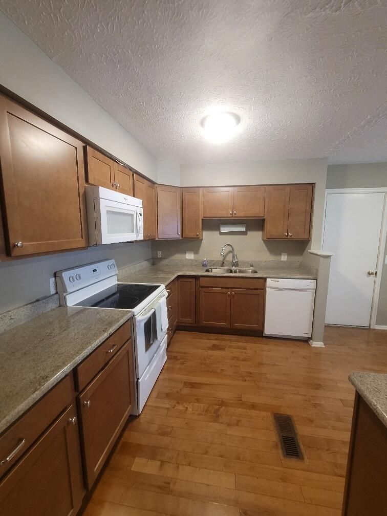A kitchen with wooden cabinets, a stove, a microwave, and a dishwasher.