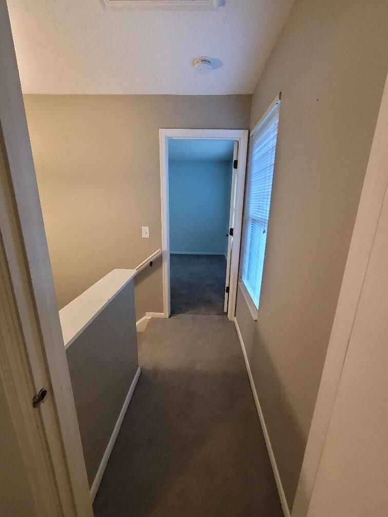 A hallway in a house with a window and a door leading to a room.