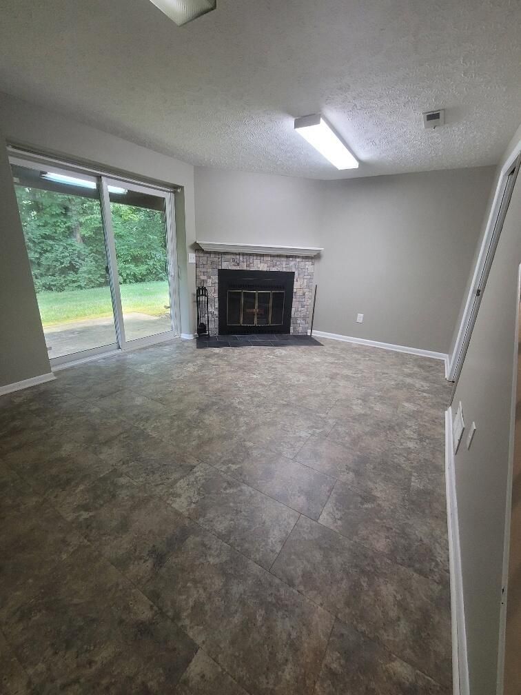 An empty living room with a fireplace and sliding glass doors.