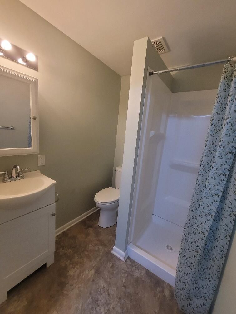 A bathroom with a toilet a sink and a shower