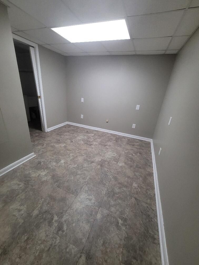 An empty basement with a tile floor and a ceiling light.
