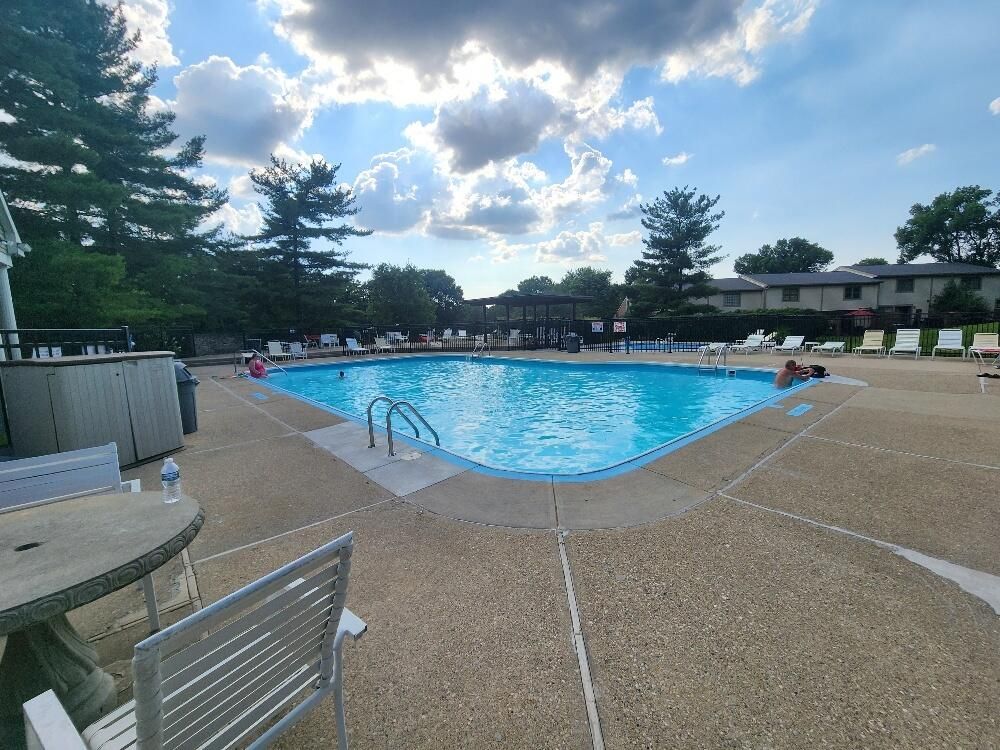 A large swimming pool with a table and chairs around it