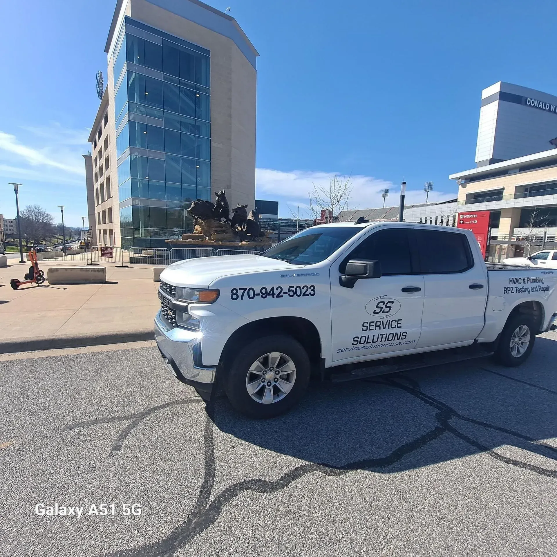 White pickup truck with company logo parked on a city street, buildings in the background.