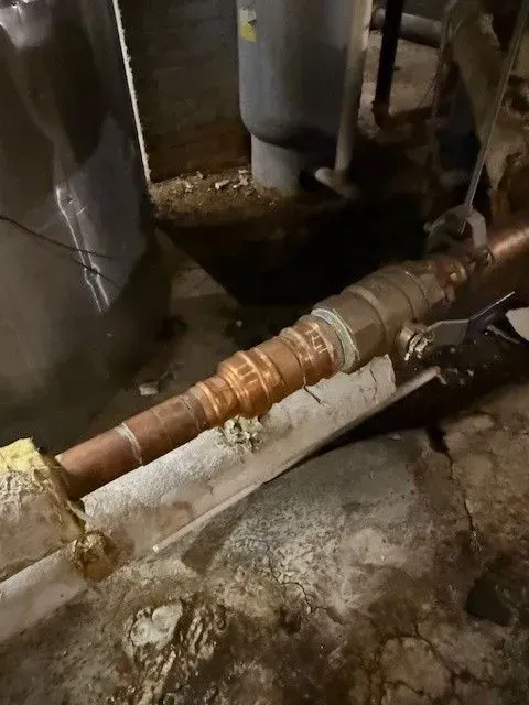 Copper pipes with corroded joints in a basement setting.