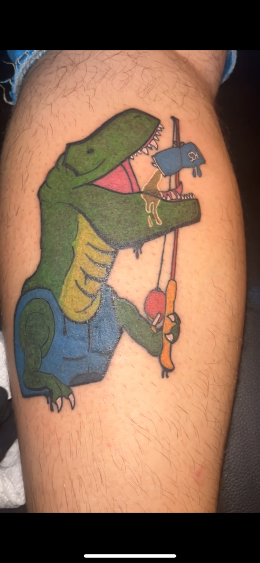 A person has a tattoo of a dinosaur on their leg.