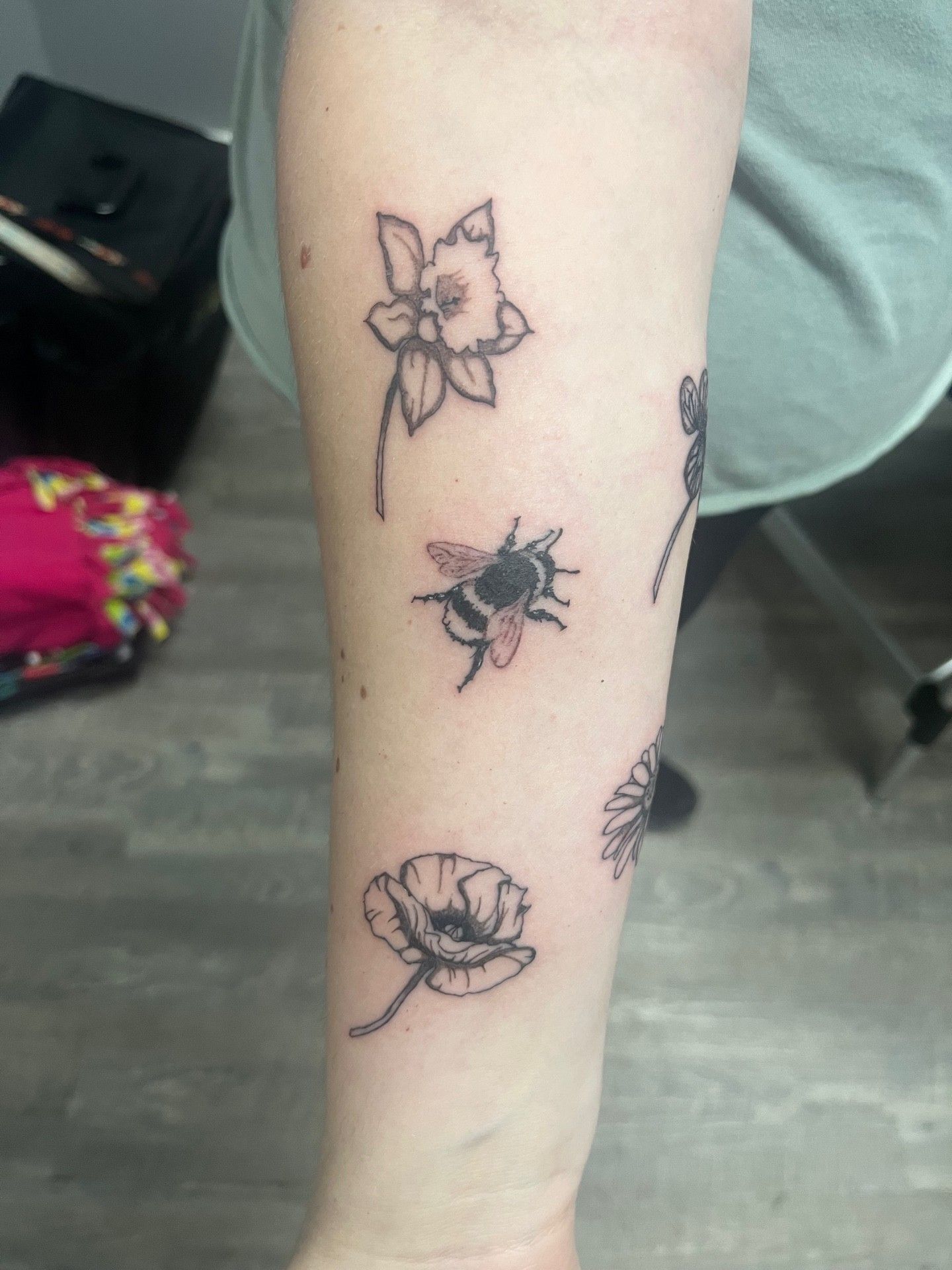 A person has a tattoo of flowers and bees on their arm