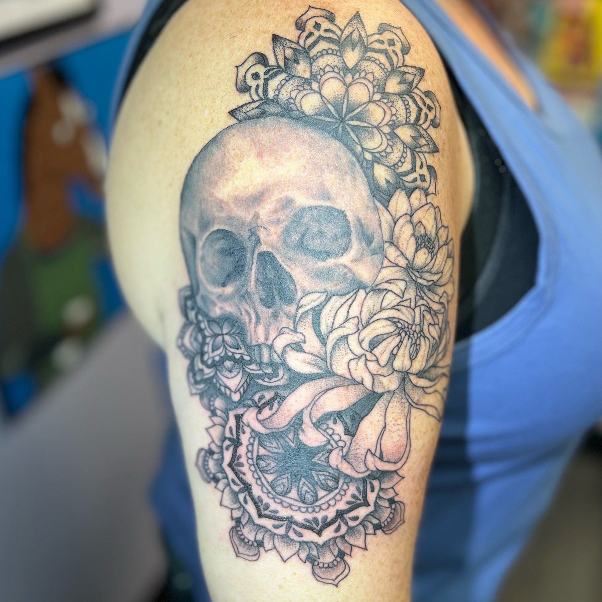 A woman has a tattoo of a skull and flowers on her arm