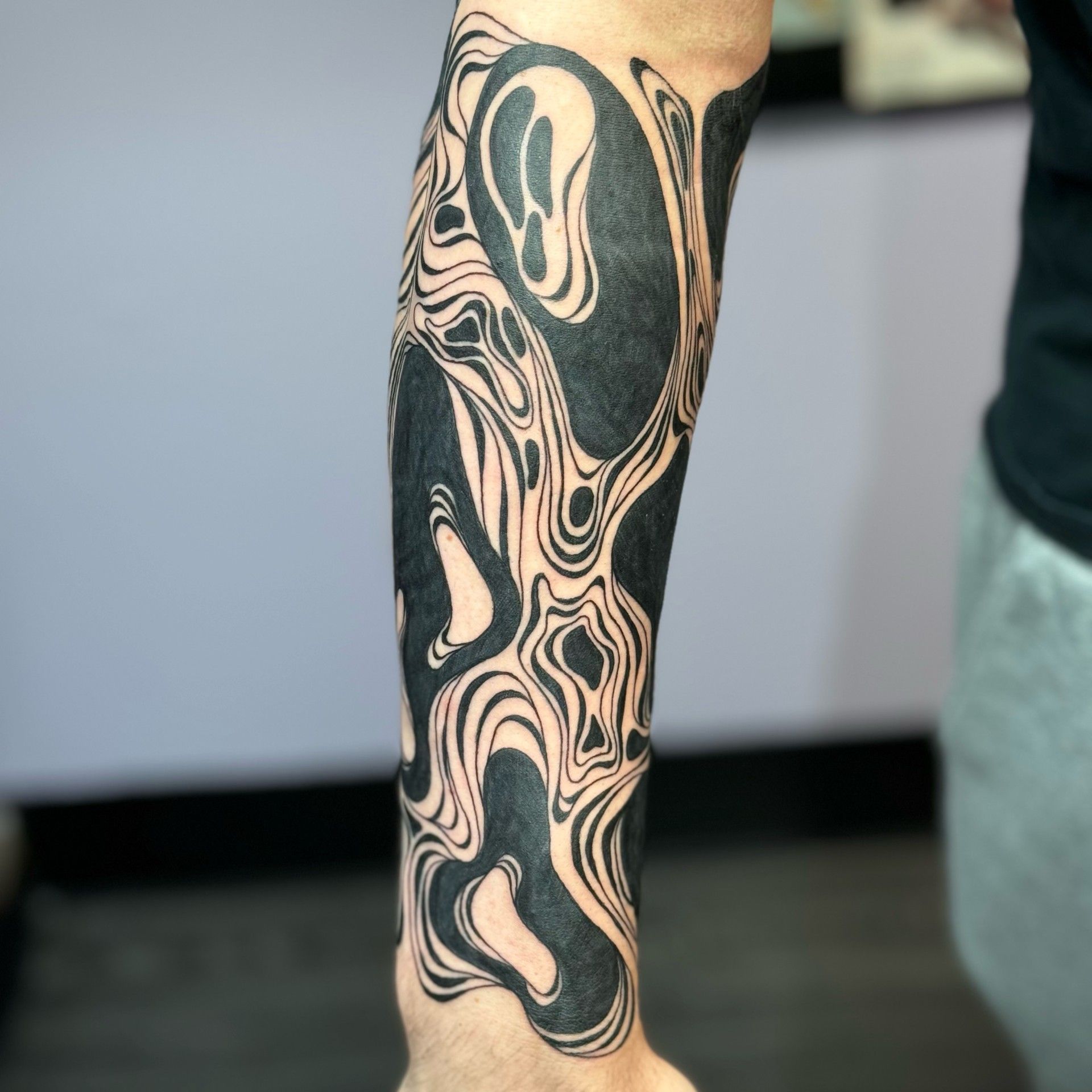 A person has a black and white tattoo on their arm