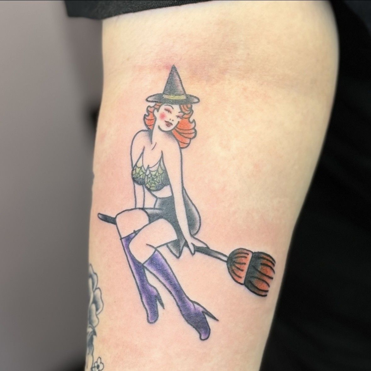 A tattoo of a witch sitting on a broom