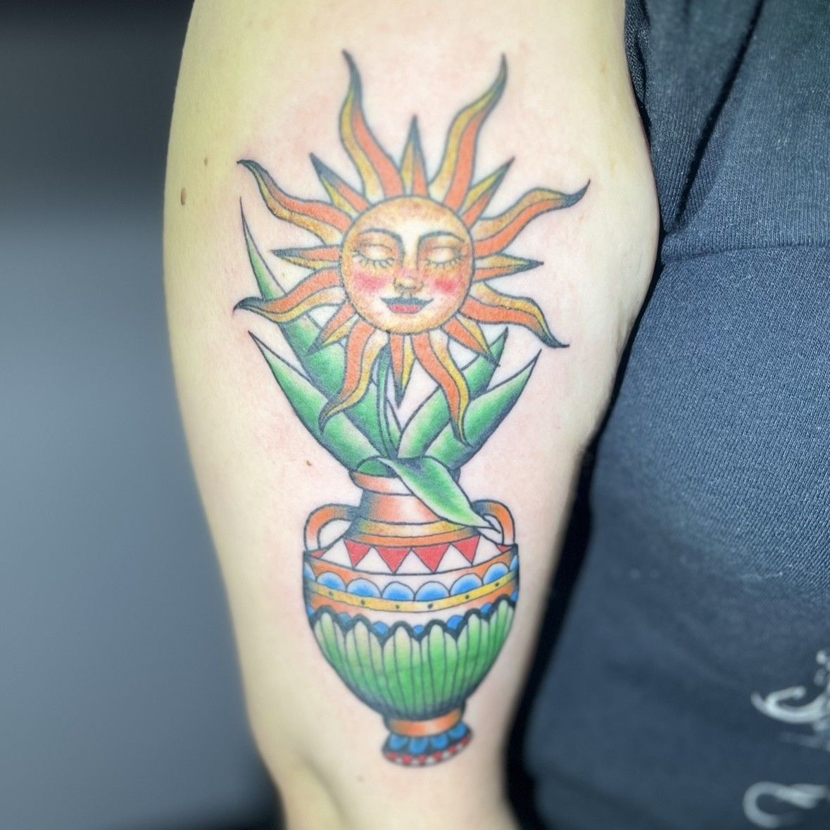 A tattoo of a sun in a vase on a person's arm