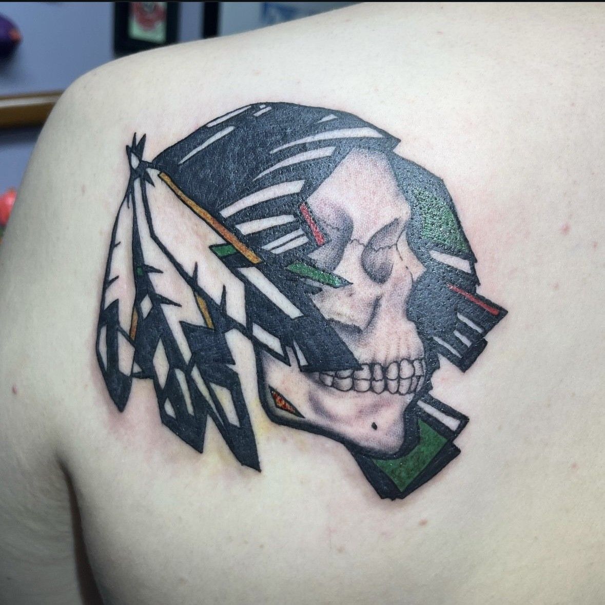 A tattoo of a skull with a feather in its mouth