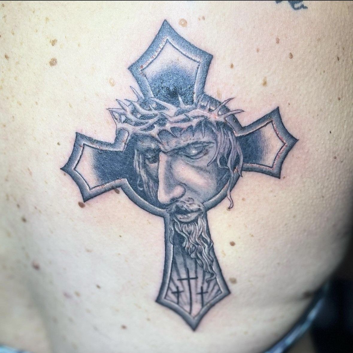 A black and white tattoo of Jesus in a cross
