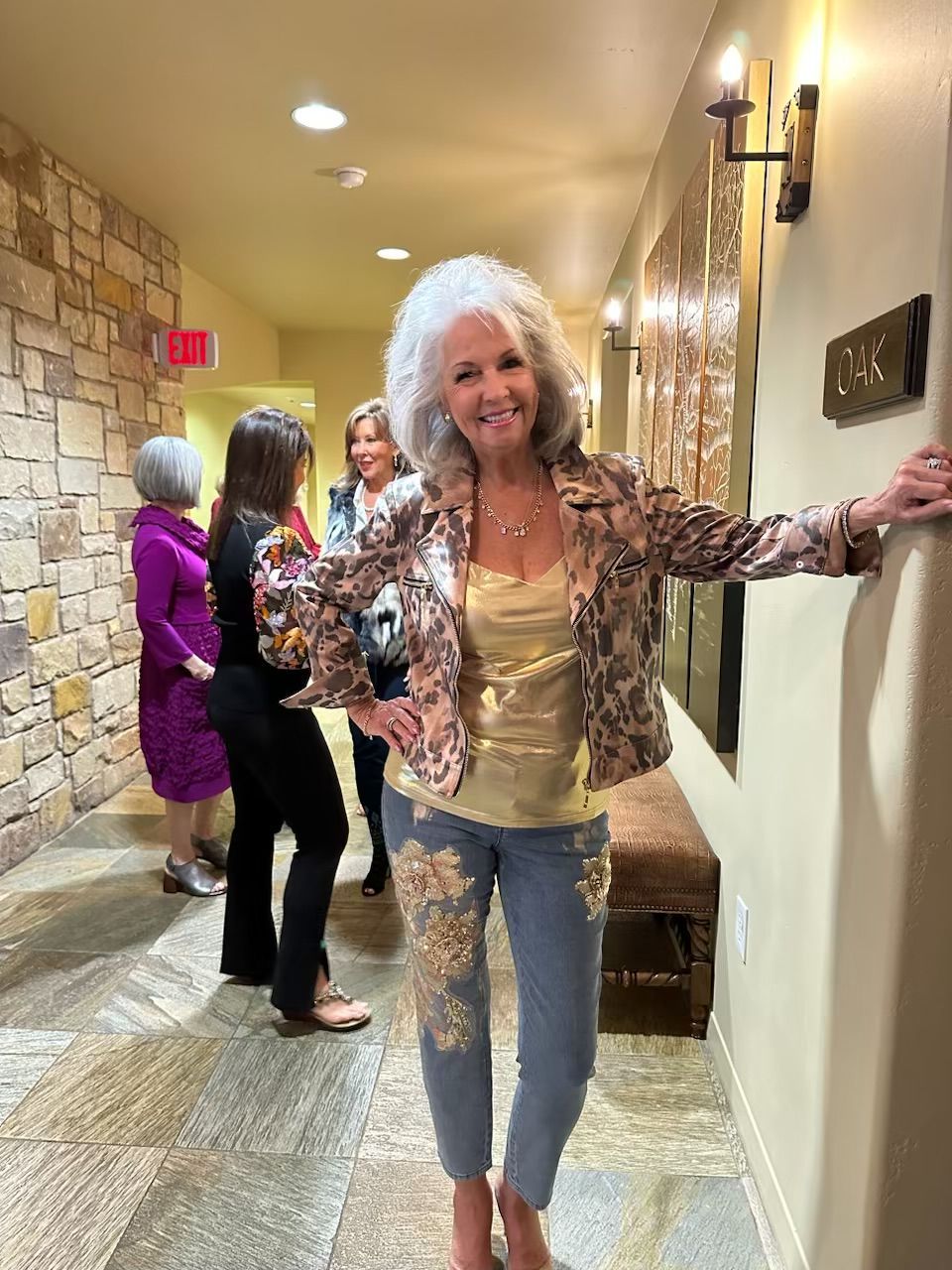 A woman is standing in a hallway with other women.