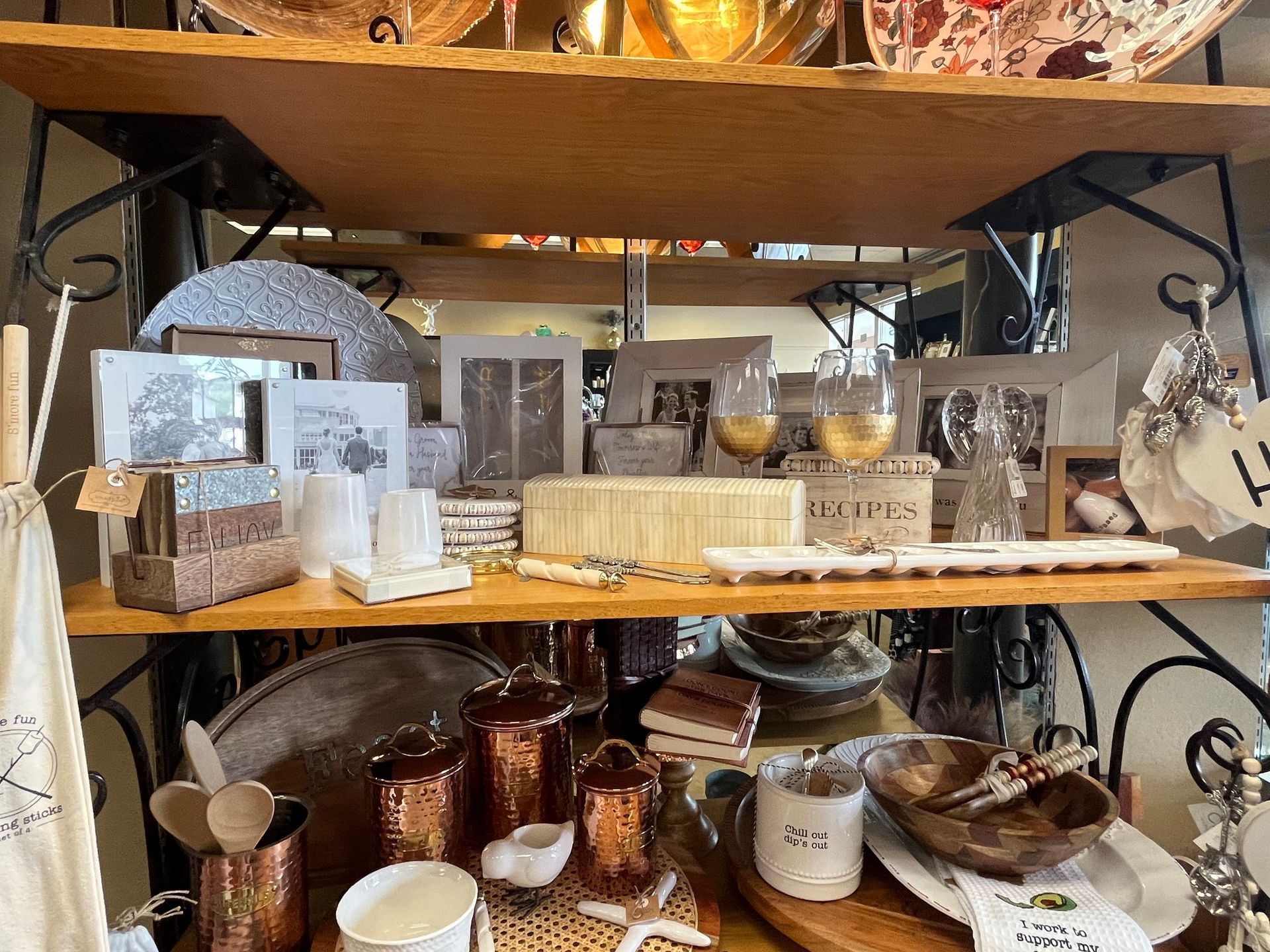 Shelves displaying home decor items, including frames, glassware, and copper pots, in a store setting.