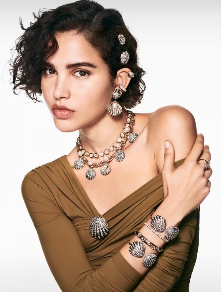 A woman wearing a necklace and bracelet with seashells on them