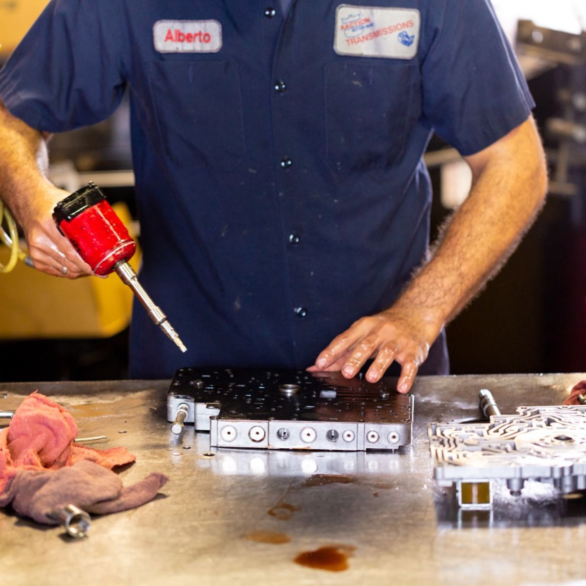 Chef using a red torch over a metal tray in a kitchen, with raw meat on the counter