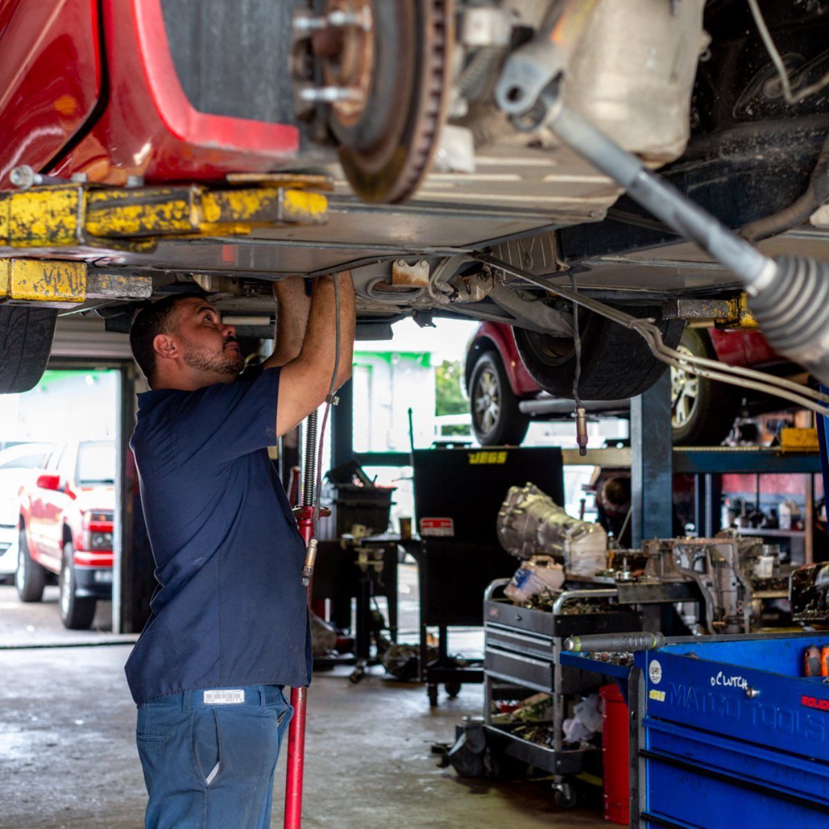 Mechanic working under a red car on a lift in an auto repair shop
