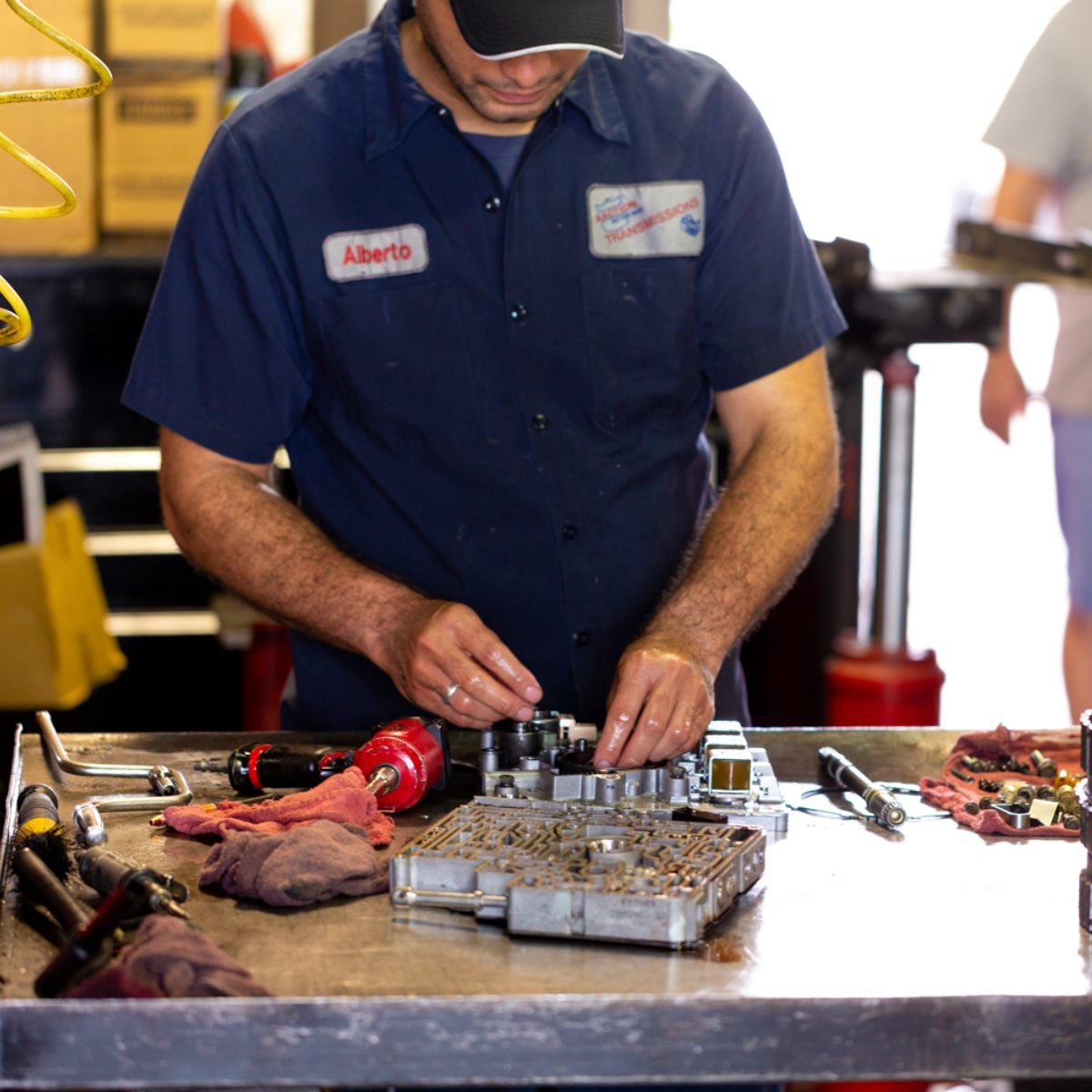 Mechanic in blue shirt working with tools on a workbench in a garage