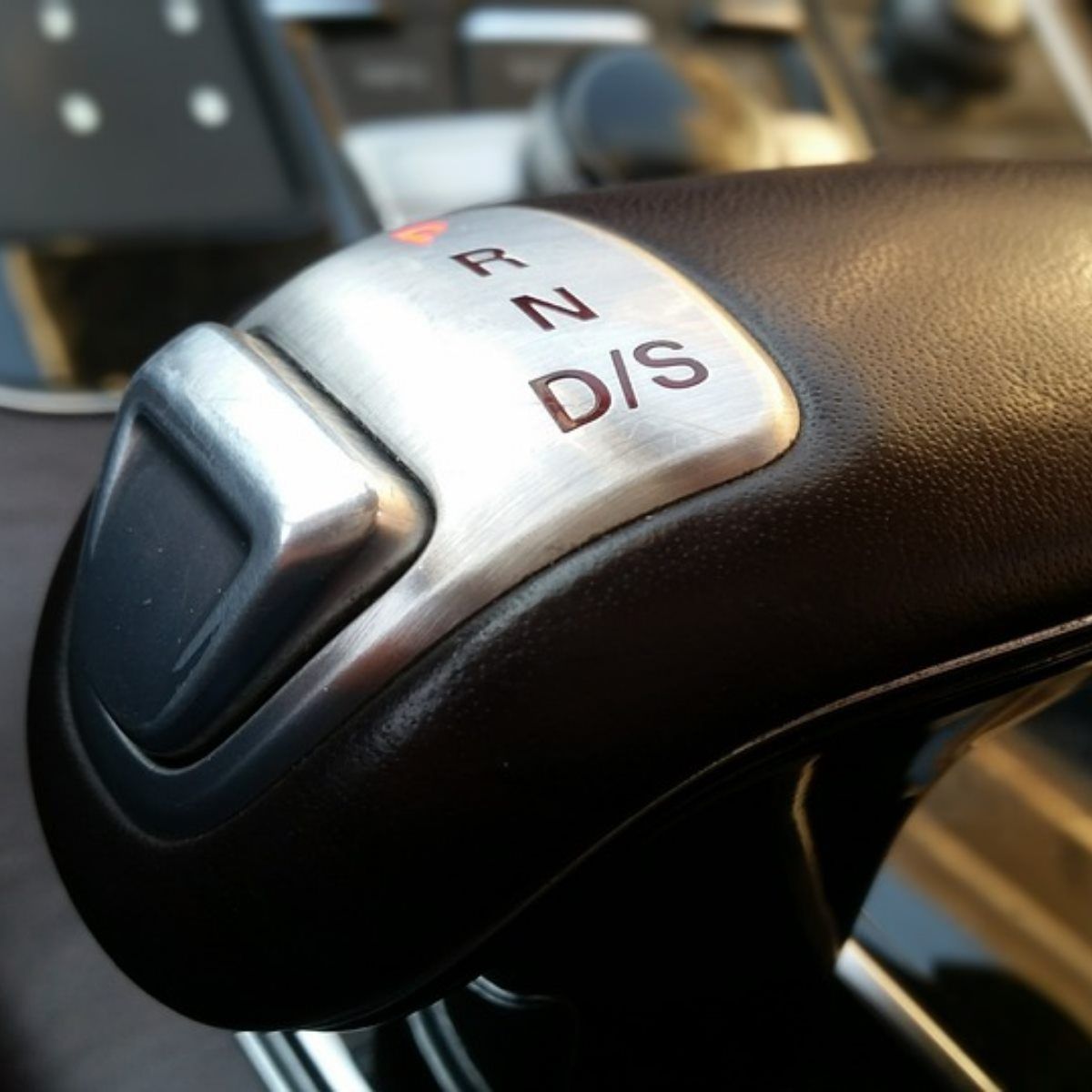 Close-up of a black gear shift lever with silver trim showing P, R, N, D/S labels