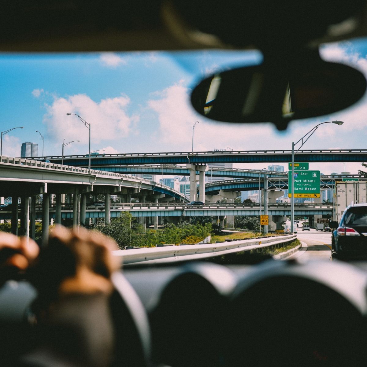 View from a car driving on a highway interchange with overpasses, traffic signs, and a city skyline ahead