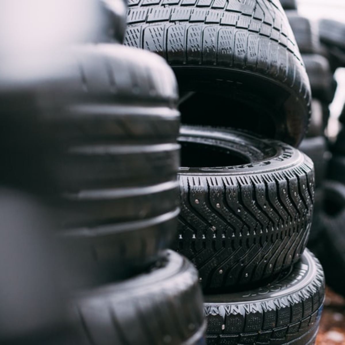 Stacks of black car tires in a warehouse, viewed close up.