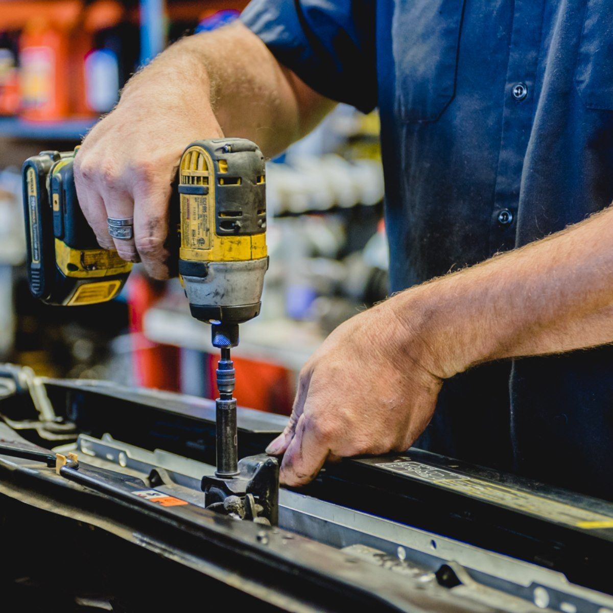 Worker using a yellow drill to assemble a metal frame in a workshop
