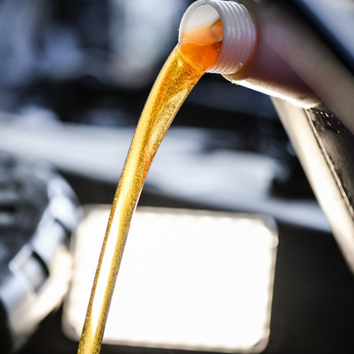 Oil being poured from a bottle into an engine.