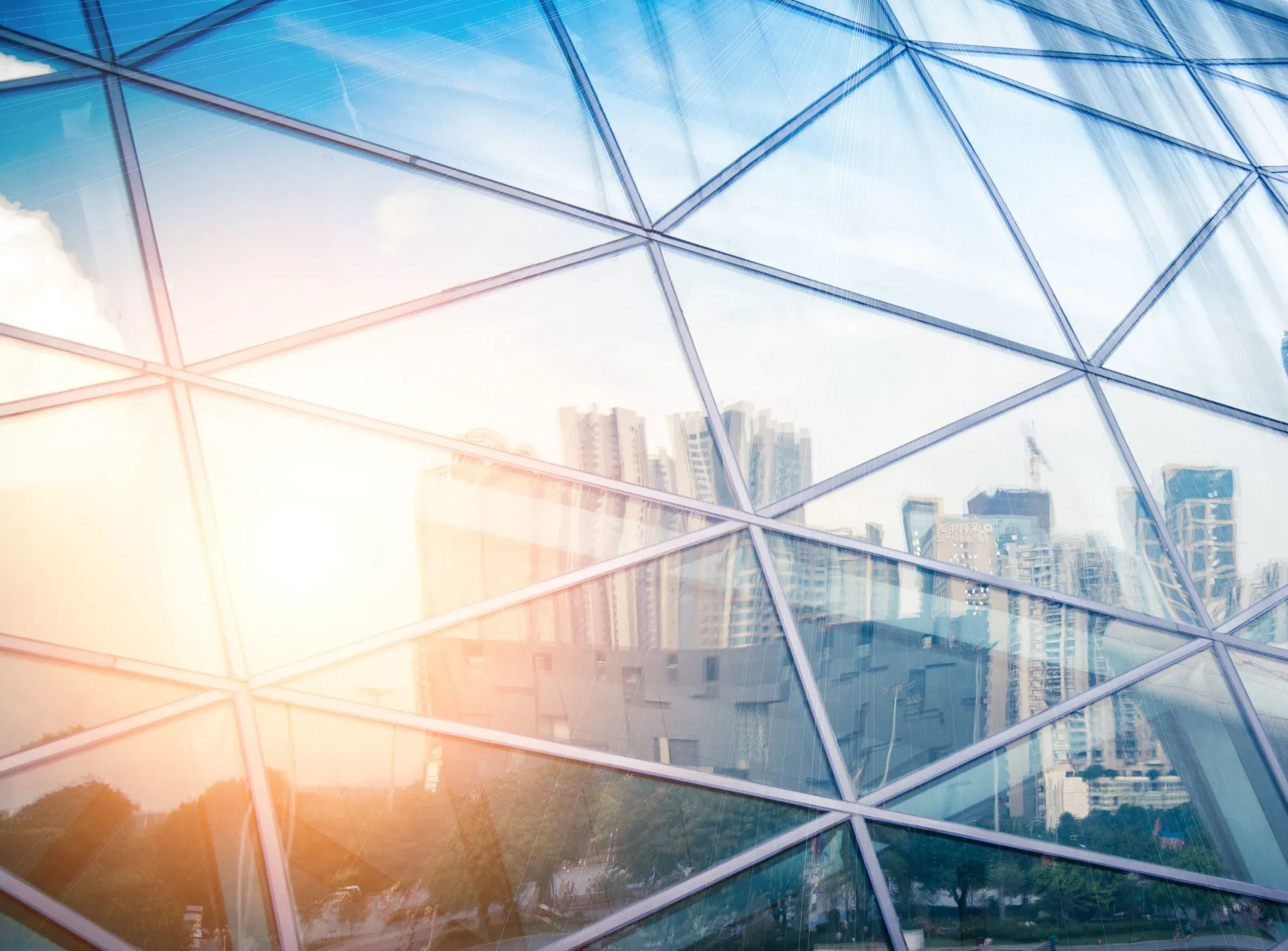 Glass building facade reflecting cityscape and sunlight.
