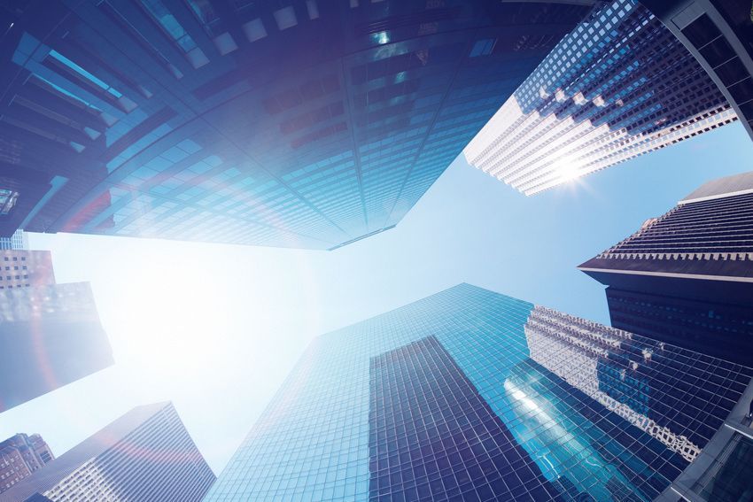 Skyscrapers reaching into a bright blue sky, viewed from below.