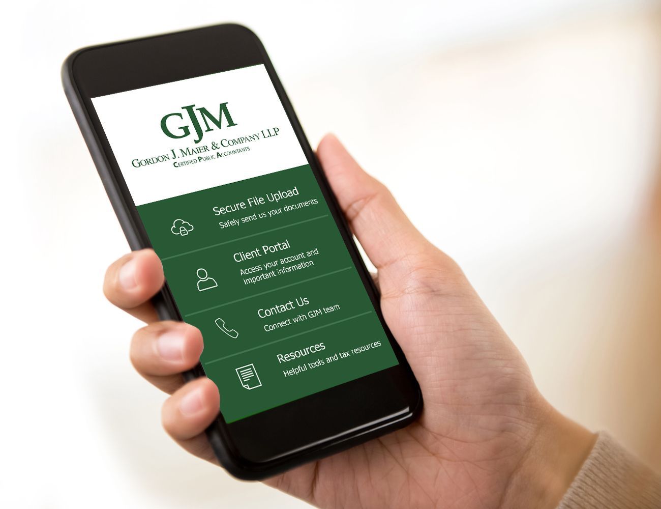 Hand holding a smartphone showing a GJM services app