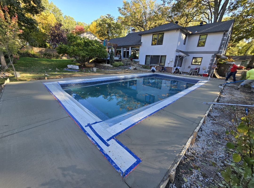 A large swimming pool is being built in the backyard of a house.