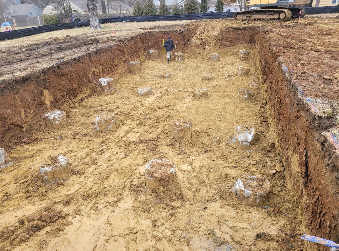 A man is standing in the middle of a large pile of dirt.