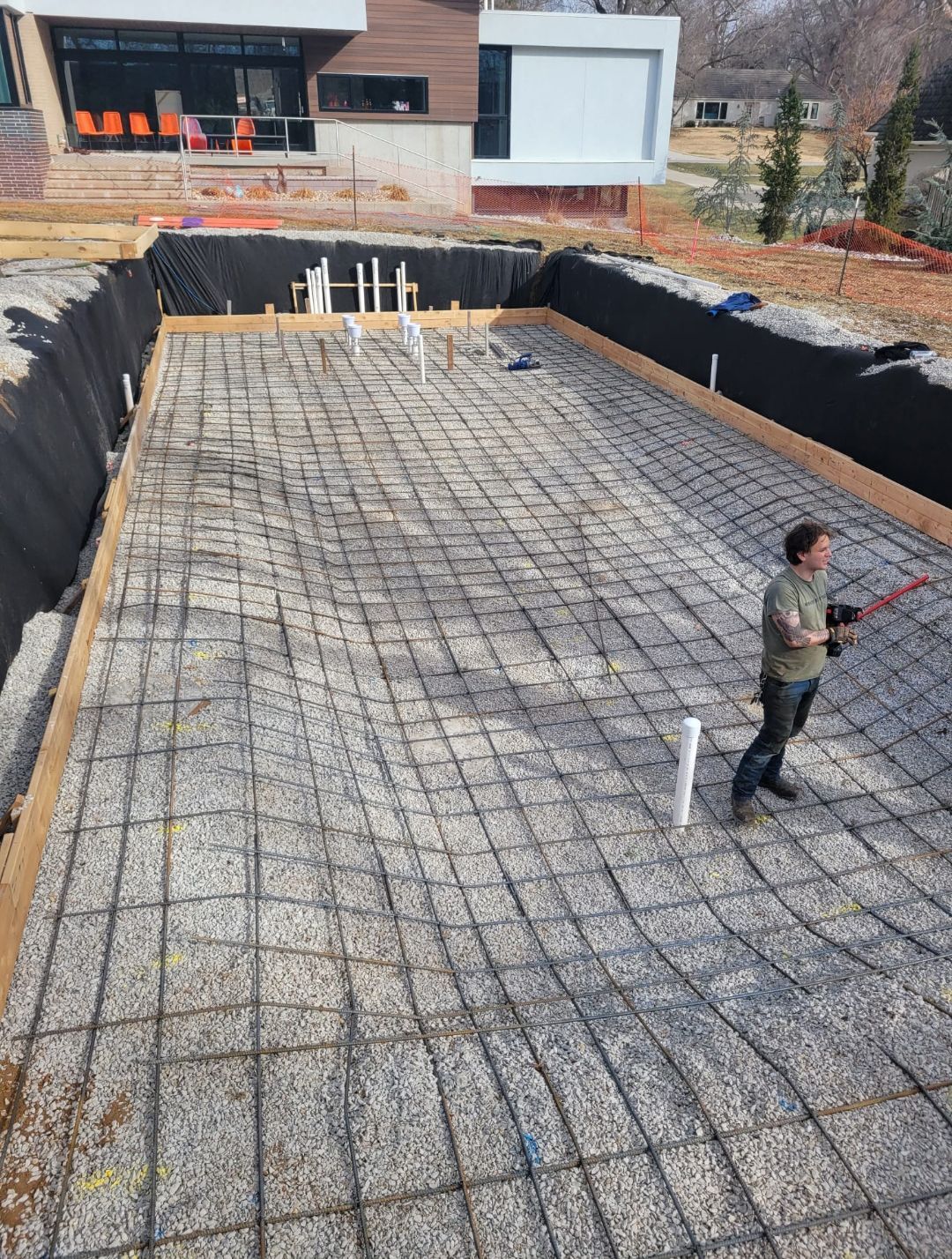 A man is standing in the middle of a swimming pool under construction.