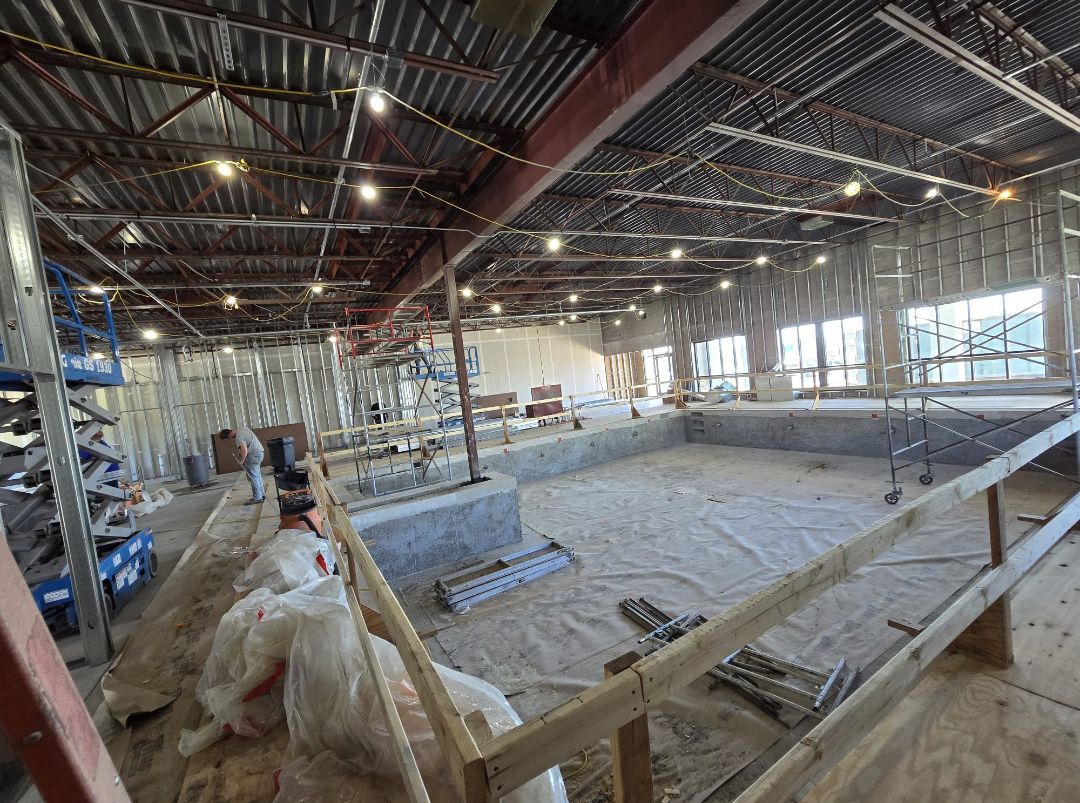 A large building under construction with a swimming pool in the middle of it.