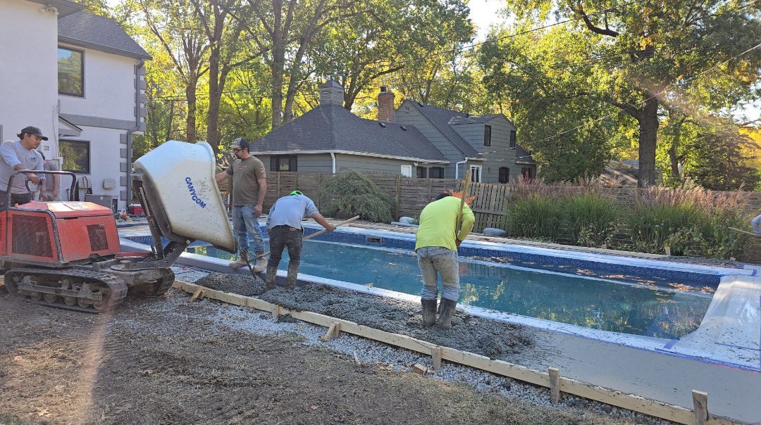 A group of construction workers are working on a swimming pool.