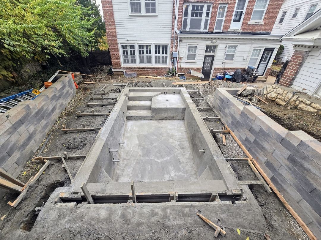 A large swimming pool is being built in the backyard of a house.