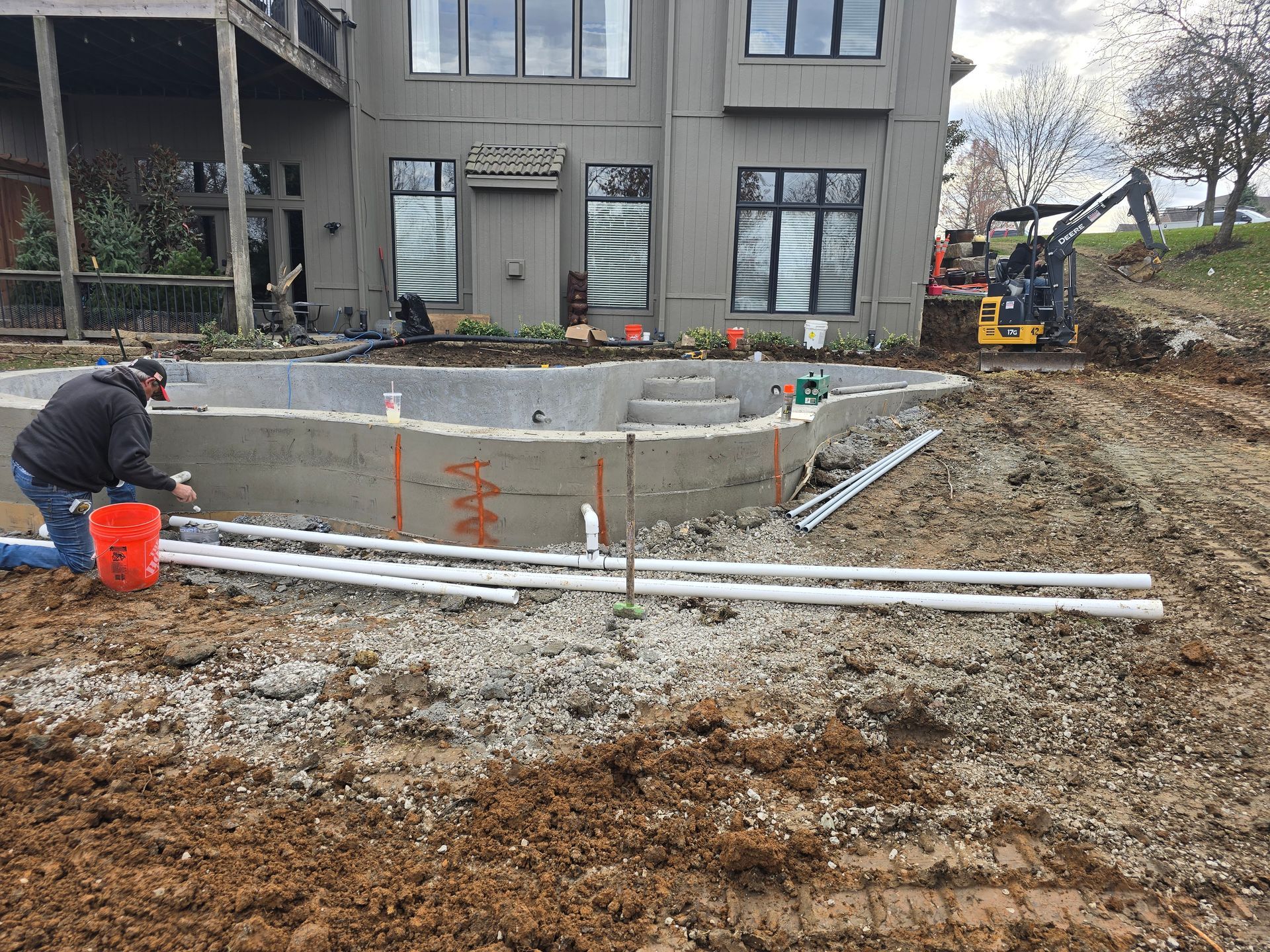A man is working on a swimming pool in front of a large house.