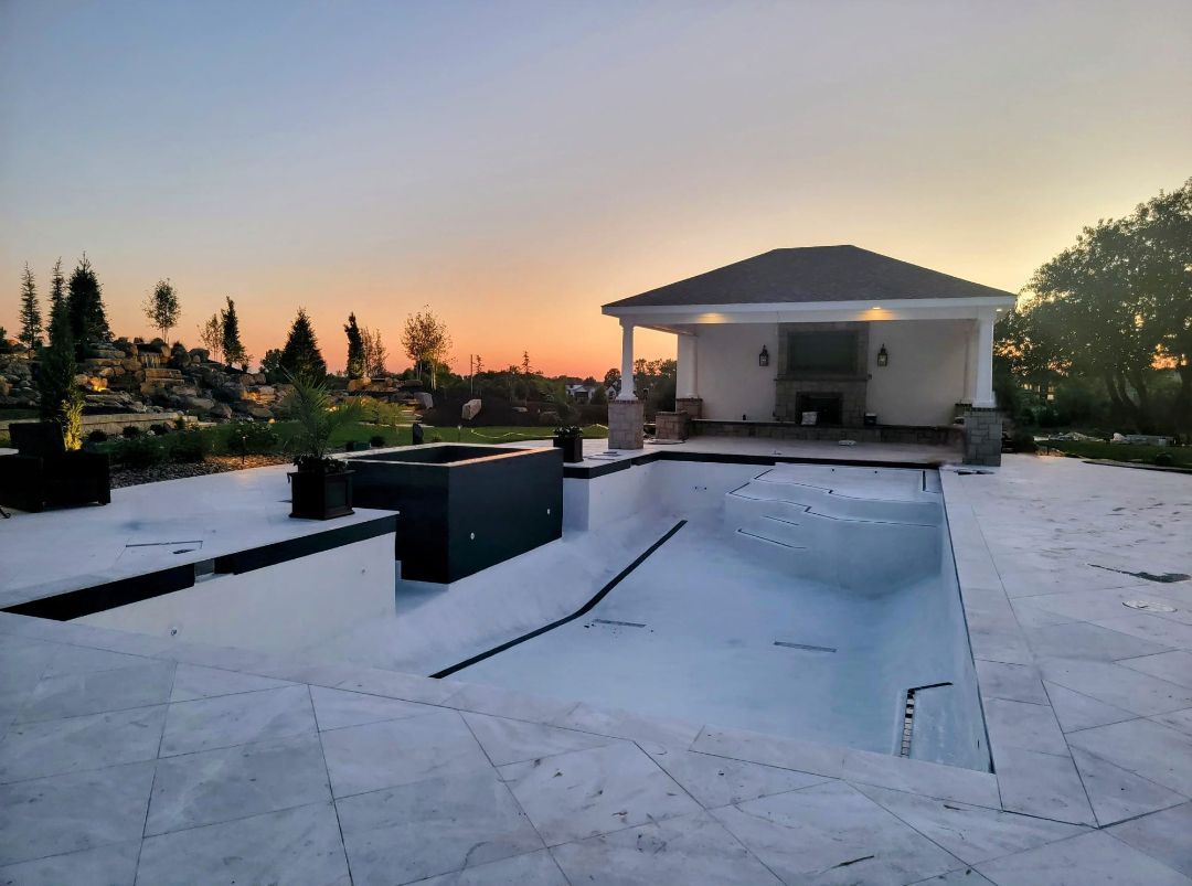 A large swimming pool with a house in the background at sunset.