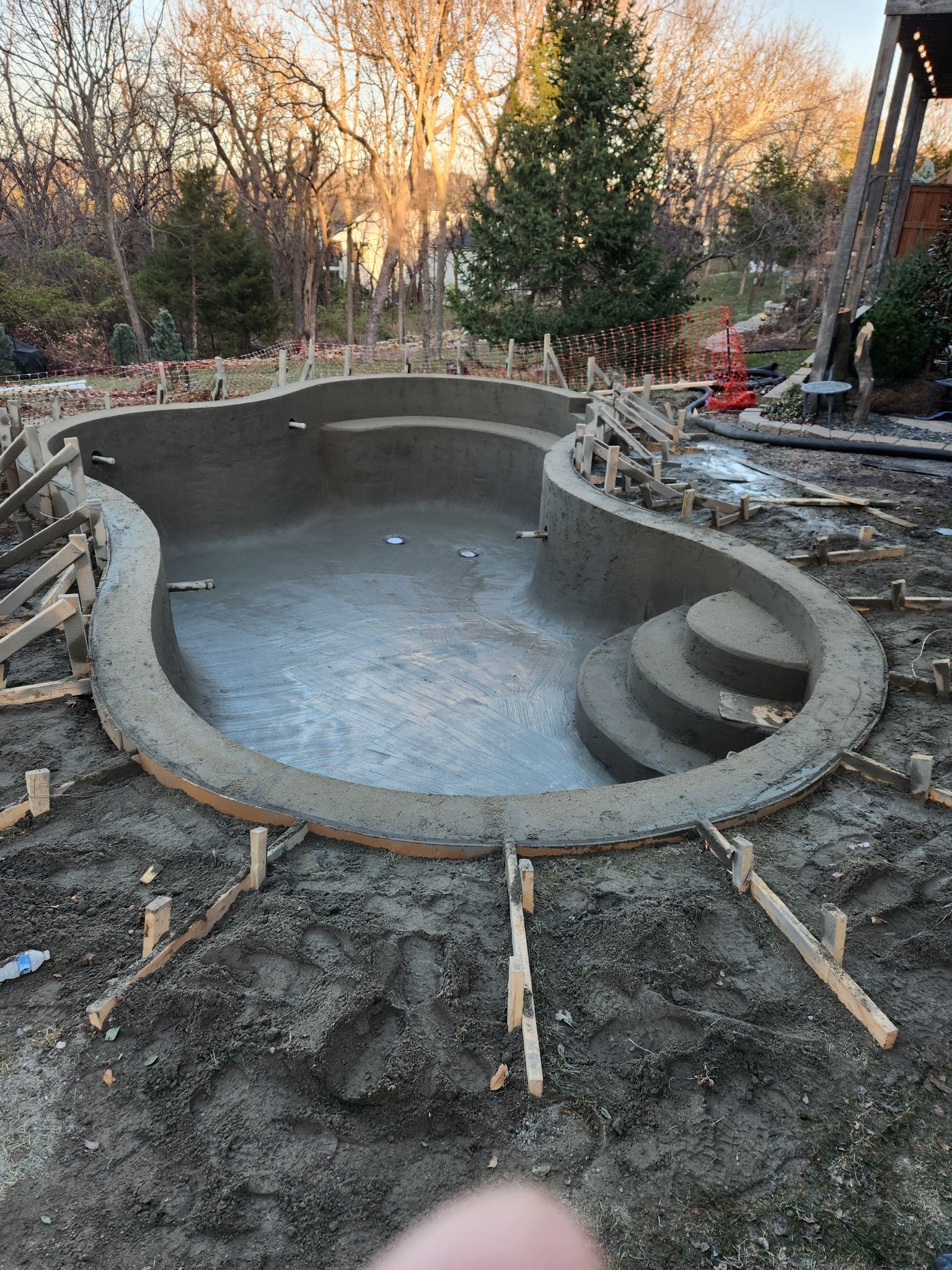 A large swimming pool is being built in a backyard.