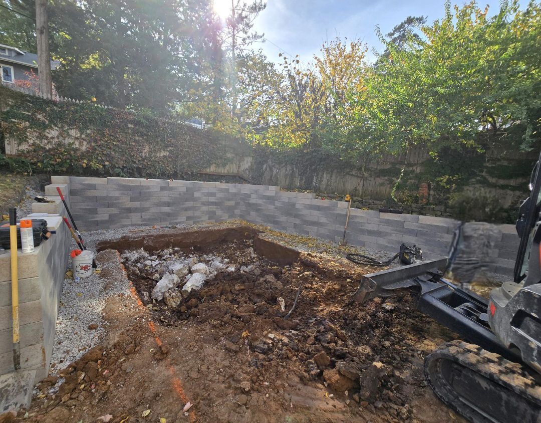 A bulldozer is digging a hole in the dirt in a backyard.