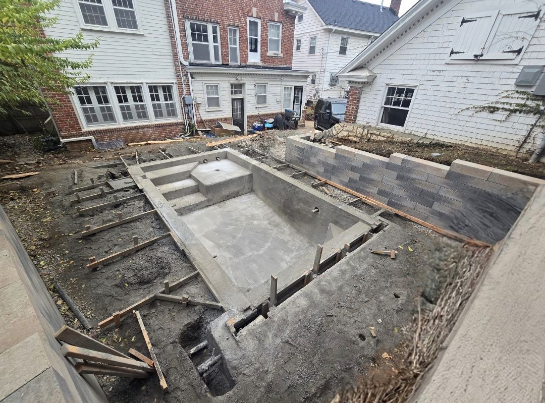 A swimming pool is being built in the backyard of a house