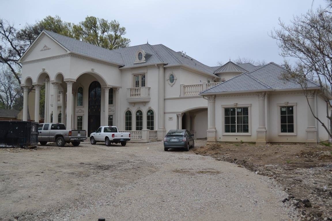 A large white house with cars parked in front of it