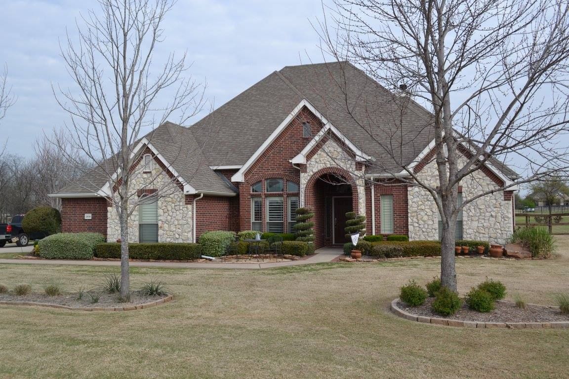 A large brick and stone house with trees in front of it