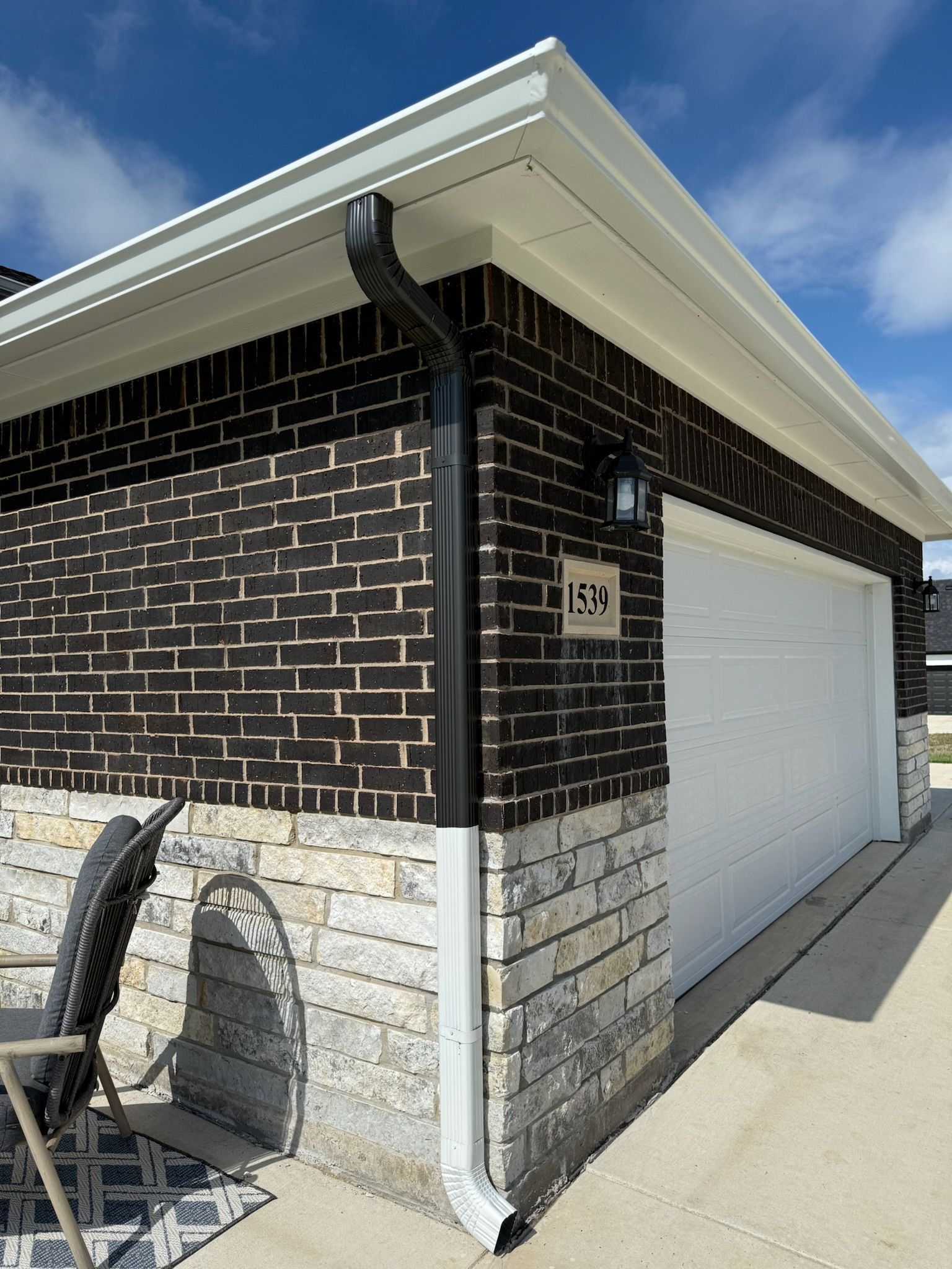 A garage with a black brick wall and a white garage door