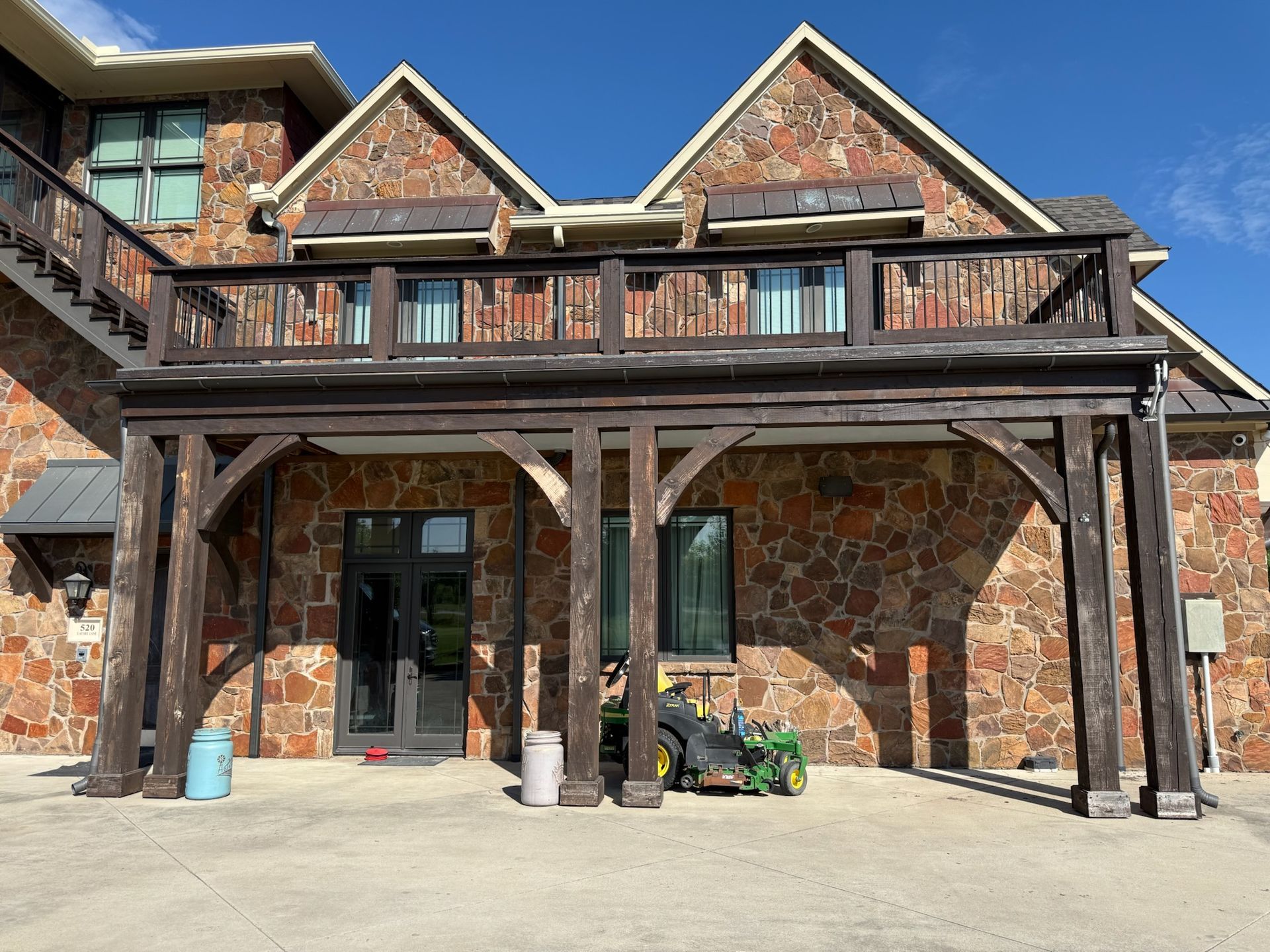A large stone house with a wooden deck and stairs.