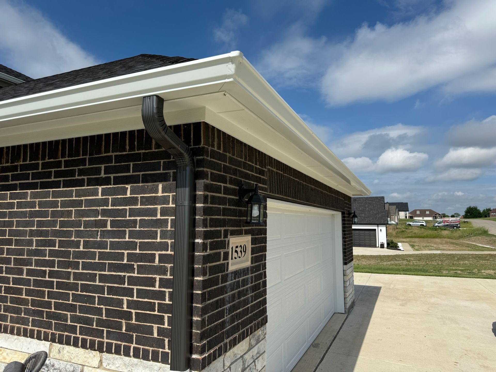 A brick house with a white garage door and a white gutter