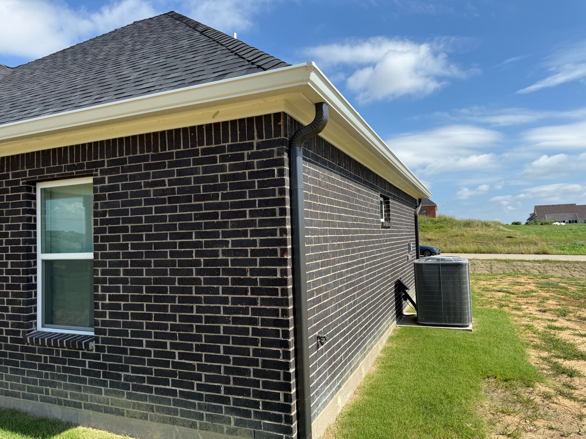 A black brick house with a window and air conditioner on the side.