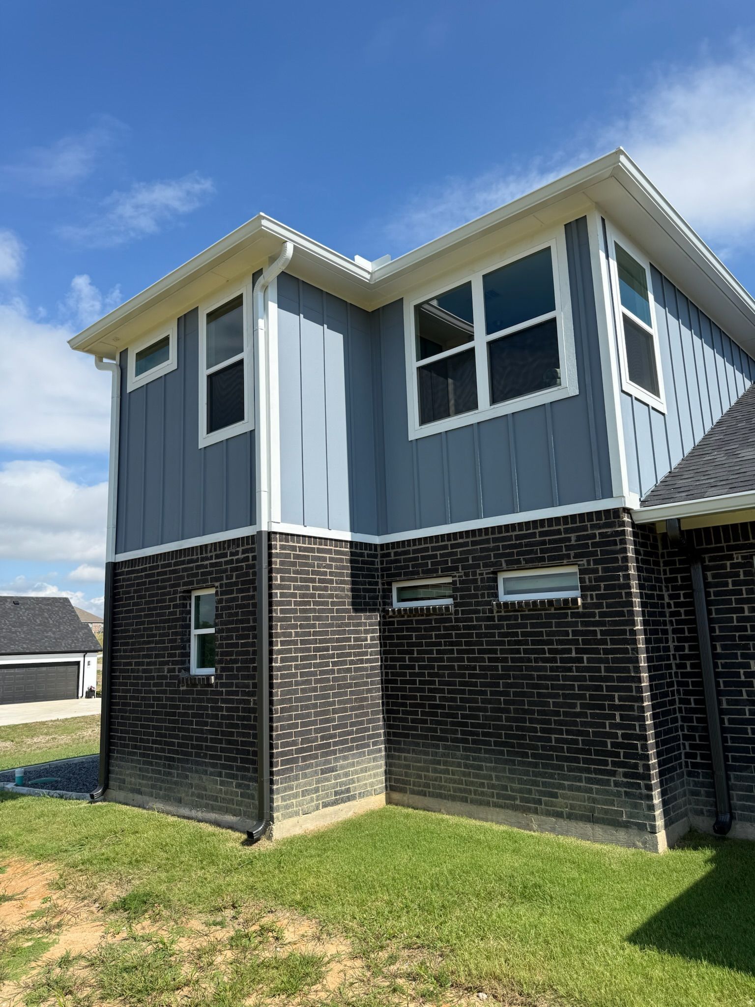 A large house with a lot of windows is sitting on top of a lush green field.