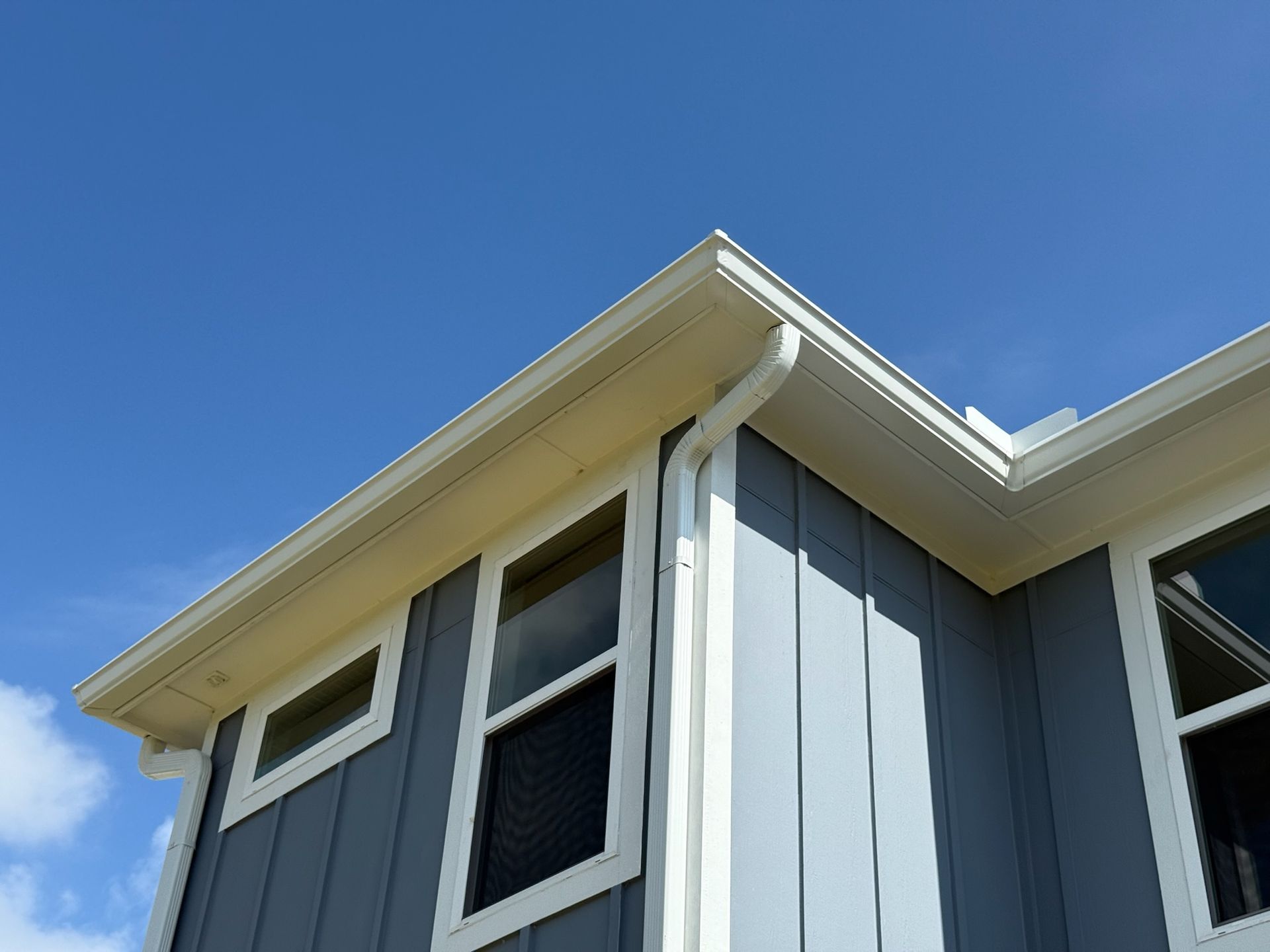 A gray and white house with a blue sky in the background.