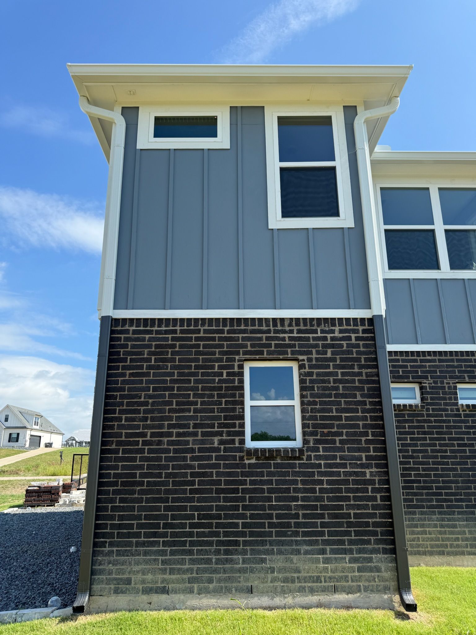 A brick house with a gray siding and white trim